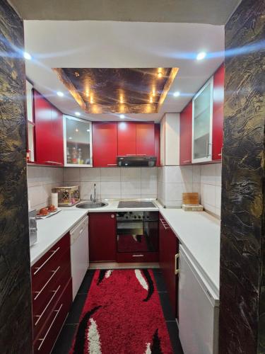 a kitchen with red cabinets and a red rug at Apartman Gold in Tuzla