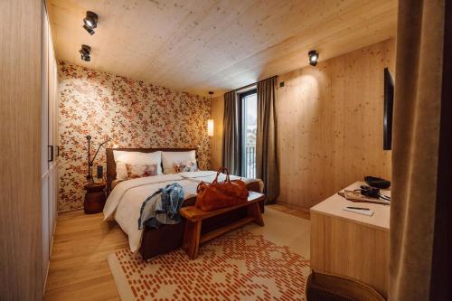 een slaapkamer met een bed en een tafel met een tas erop bij Boutique Hotel Das Rivus in Leogang