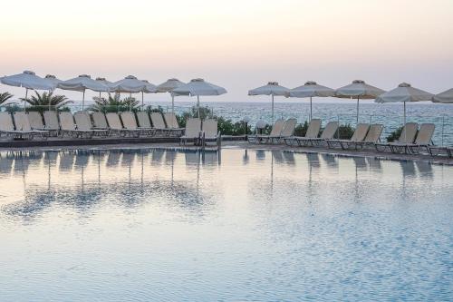 a row of chairs and umbrellas next to the water at Maritimo Beach Hotel in Sisi