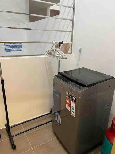 a washing machine in a room next to a staircase at LV Homestay @ Gala Residence in Kuching