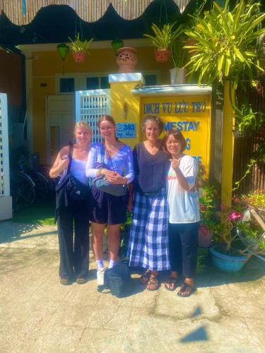 a group of women standing in front of a yellow building at An Bang Sea Adventure Homestay Hoi An in Hoi An