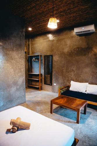a room with a bed and a table and a couch at The Ohm Siargao Resort in General Luna