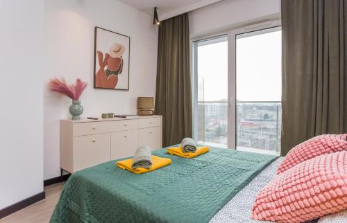 a bedroom with a bed with towels and a window at Urban Jungle apartament Epsilon in Białystok
