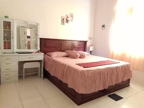 a bedroom with a bed with a dresser and a mirror at Wambuliga Homestay in Waha