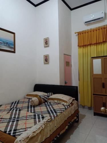 a bedroom with a bed and a yellow curtain at Wambuliga Homestay in Waha