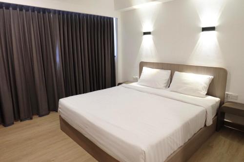 een slaapkamer met een groot wit bed met 2 kussens bij U-Thong Hotel in Phitsanulok