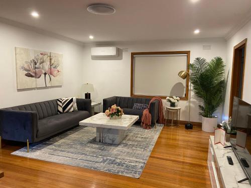 una sala de estar con un sofá y una mesa en Style/Comfort/Spacious 4 bedroom house plus study, en Melbourne
