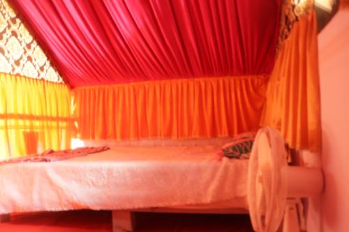 a bedroom with red curtains and a bed with a chair at Ramu Green Lake Cottage in Mysore