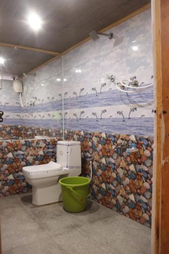 a bathroom with a toilet and a mosaic wall at Ramu Green Lake Cottage in Mysore