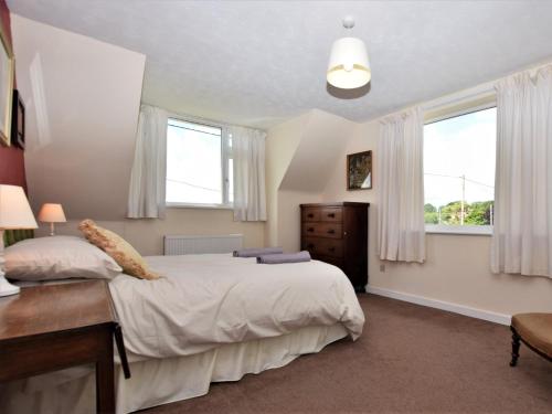 a bedroom with a large bed and two windows at 3 Bed in Great Snoring KT075 in Great Snoring