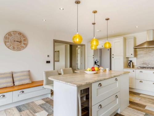 a kitchen with white cabinets and yellow pendant lights at 3 Bed in Bovey Tracey 64380 in Bovey Tracey
