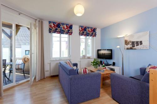 uma sala de estar com duas cadeiras azuis e uma televisão em Ahlbecker Höhe App Strandkorb em Ahlbeck