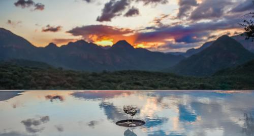 a reflection of a wine glass in a lake at sunset at umVangati House in Hoedspruit