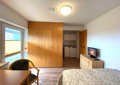 1 dormitorio con cama, mesa y cocina en Süderhaus Hiddensee App 3, en Neuendorf