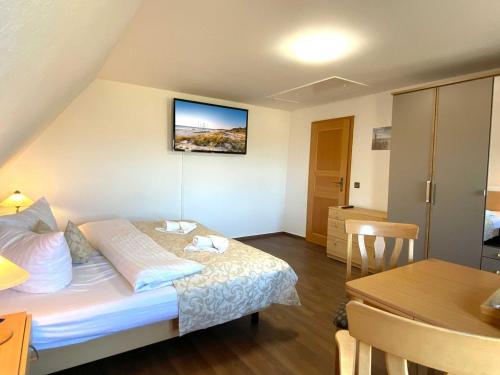 a bedroom with a bed and a table and a television at Süderhaus Hiddensee App 13 in Neuendorf