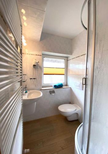 a bathroom with a sink and a toilet and a window at Süderhaus Hiddensee App 2 in Neuendorf