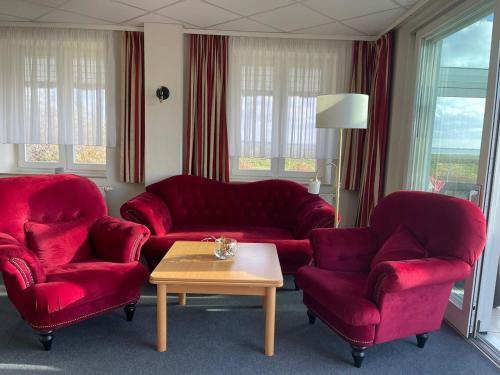 una sala de estar con 2 sofás rojos y una mesa. en Süderhaus Hiddensee App 15, en Neuendorf