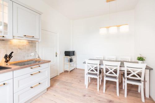 eine Küche mit weißen Schränken und einem Tisch mit Stühlen in der Unterkunft Villa Albus App 2 in Ahlbeck