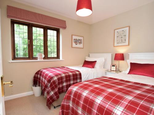 two beds in a bedroom with red and white blankets at 2 Bed in Moreton-In-Marsh 75870 in Whichford