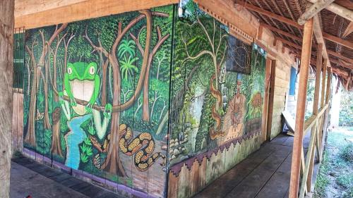 YAKU lodge & camping في Padre Cocha: لوحة جدارية على جانب مبنى مع غابة
