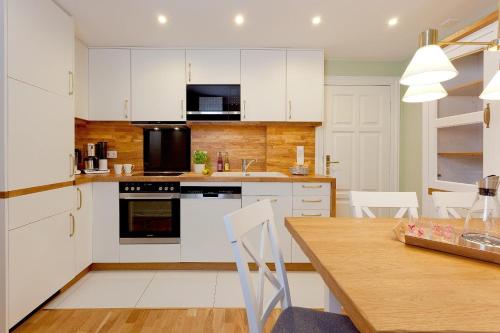 uma cozinha com armários brancos e uma mesa de madeira em Villa Waldschloss App 2 em Bansin