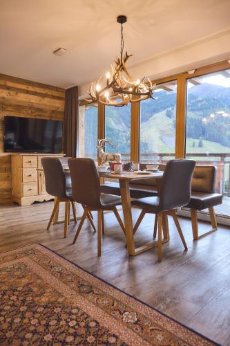 a dining room with a table and chairs and a chandelier at AlpenParks Hotel & Apartment Sonnleiten in Saalbach Hinterglemm