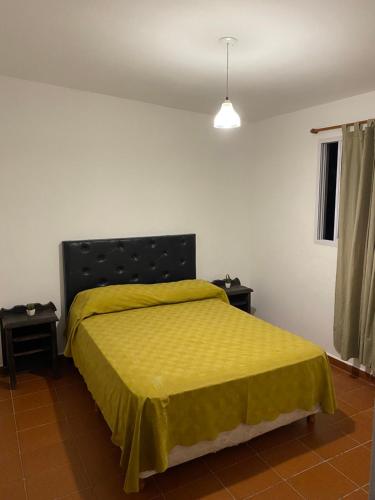 une chambre avec un lit avec un couvre-lit jaune dans l'établissement departamentoAA, à Villa Carlos Paz