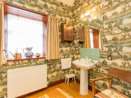 a bathroom with a sink and green and white wallpaper at 6 bed in Lairg CA301 in Lairg