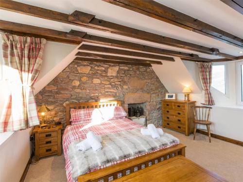 Un dormitorio con una pared de piedra y una cama en 2 bed in Loch Ness CA315, en Drumnadrochit