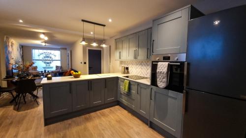 a kitchen with gray cabinets and a black refrigerator at Stylish 2 bed townhouse in Brighton & Hove