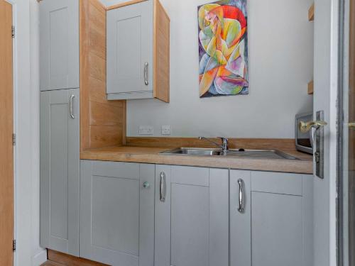 a kitchen with white cabinets and a sink at 1 Bed in Isle of Purbeck IC176 in Worth Matravers