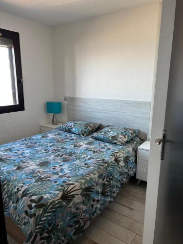 une chambre avec un lit avec une couette bleue dans l'établissement T2 Face à la Mer & Village de Noël 5 min à pied, au Barcarès