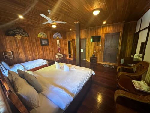 a bedroom with two beds and a ceiling fan at KhounPhet GuusetHous Luangprabang in Luang Prabang