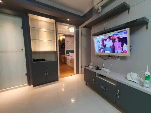 sala de estar con TV de pantalla plana en la pared en Apartemen Gading Icon, en Yakarta