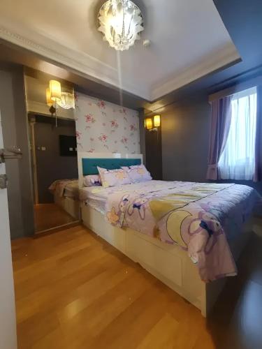 1 dormitorio con cama y lámpara de araña en Apartemen Gading Icon, en Yakarta
