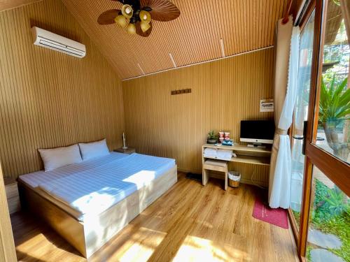 a bedroom with a bed and a desk with a television at Lá Garden Homestay in Long Xuyên