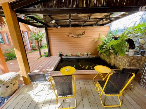 a patio with a fish pond and yellow chairs at Lá Garden Homestay in Long Xuyên
