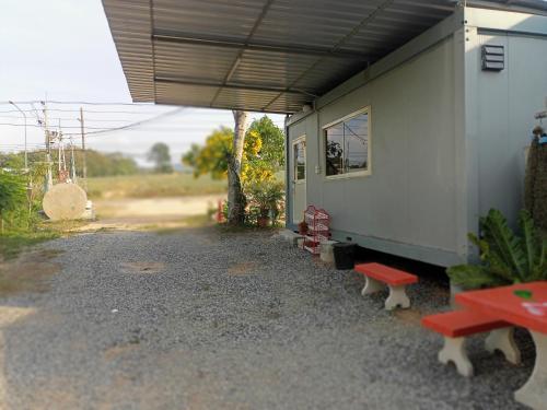 ein Haus mit einer Gruppe Bänken daneben in der Unterkunft ปวินท์เกสต์เฮาส์ in Ban Pong Khlum