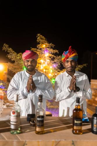 two men in white robes praying in front of a table at Nomads heaven desert camp jaisalmer in Jaisalmer