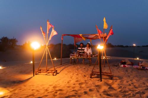 two people sitting at a table on the beach at night at Nomads heaven desert camp jaisalmer in Jaisalmer