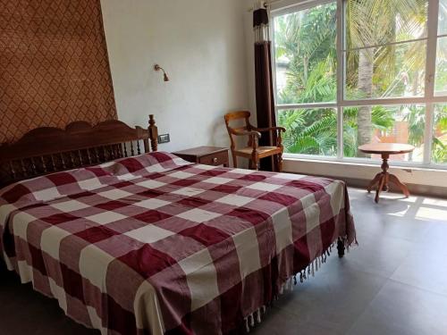 1 dormitorio con 1 cama con manta a cuadros en Adams Wood House Ayurveda Homestay Kochi, en Kochi