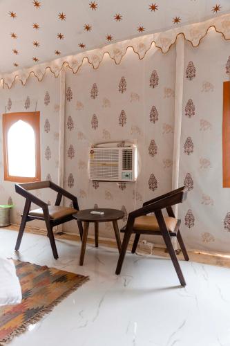 a living room with two chairs and a fan at Nomads heaven desert camp jaisalmer in Jaisalmer