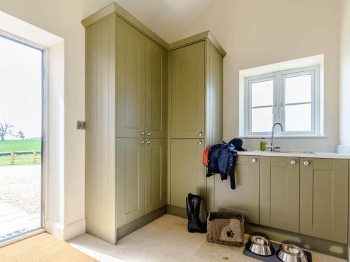 eine Küche mit grünen Schränken, einem Waschbecken und einem Fenster in der Unterkunft 4 Bed in Bedale 80704 in Finghall
