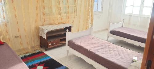 Chott MeriemにあるDar Souadeのベッド2台とテーブルが備わる小さな客室です。