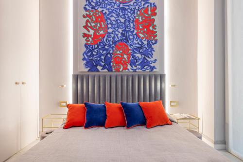 łóżko z pomarańczowymi i niebieskimi poduszkami w pokoju w obiekcie Falcone, 5 - Downtown apartment w Mediolanie