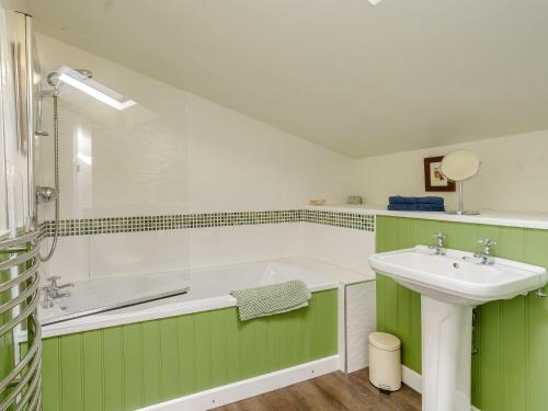 a green and white bathroom with a sink and a tub at 2 bed in Llangynidr BN023 in Llangynidr