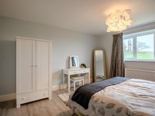 a bedroom with a bed and a desk and a chandelier at 3 Bed in Worth Matravers 80578 in Worth Matravers