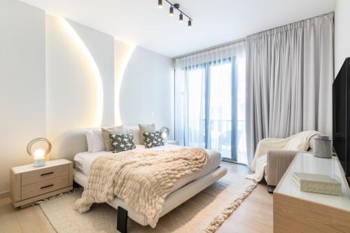 a white bedroom with a bed and a large window at Stunning Palm Villa with Rooftop Garden, Resort Style Pool and Beach by Exclusive Holiday Homes in Dubai