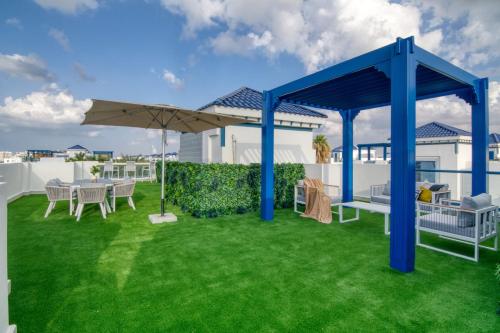 a patio with a table and an umbrella on a lawn at Stunning Palm Villa with Rooftop Garden, Resort Style Pool and Beach by Exclusive Holiday Homes in Dubai