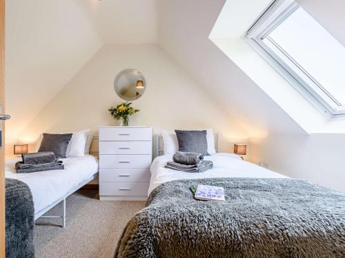 a attic bedroom with two beds and a window at 2 Bed in Bude 82163 in Bude